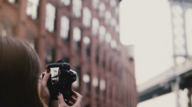 Arkadan görünüm profesyonel kadın fotoğrafçı fotoğraf makinesi ile Brooklyn Köprüsü'nün Dumbo District, Istanbul 4 k çekiyor.