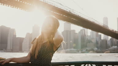 Poz, güneş gözlüğü üzerinde koyarak kameraya Brooklyn Köprüsü'nün New York manzarası 4 k arıyorsunuz mutlu oynak beyaz genç bir kadın.