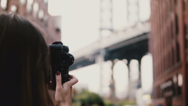 カメラ背面の女性旅行ブロガーは、ダンボ、ニューヨーク市、歩く距離の 4 k のブルックリン橋の写真. — ストック動画