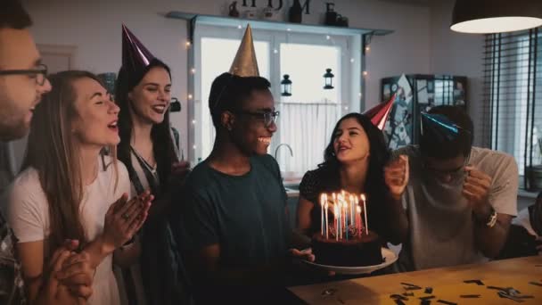 Щасливі афроамериканець людиною, тримаючи народження торт, танцювали і святкували в багатоетнічній партія з друзями повільний рух. — стокове відео