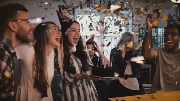 Beautiful European girl holds birthday cake, celebrates with happy multiethnic friends and amazing confetti slow motion. — Stock Video