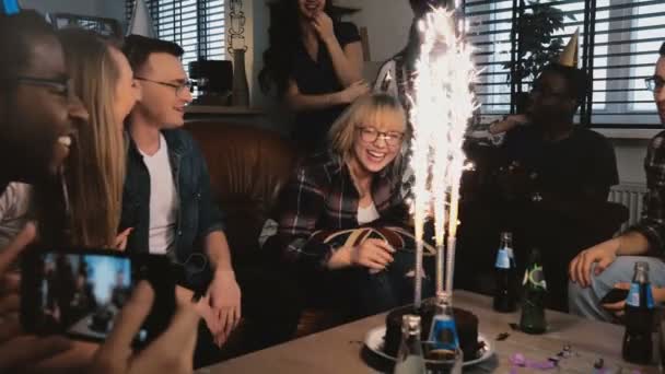 Schüchternes Geburtstagskind dankt multiethnischen Freunden für Geburtstagsparty mit funkelndem Feuerwerkskuchen und lustigen Hüten in Zeitlupe. — Stockvideo