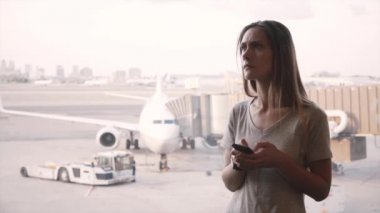 Genç kafkas kadın gezgin smartphone kullanır, duyuru yakın havaalanı pencere dinledikten sonra buolduğunun.