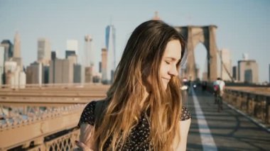 Sıcak güneşli havanın tadını, kafa dönme ve Brooklyn köprüsünde 4 k gülümseyen kamera bakıyor güzel beyaz kız.