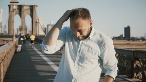 Portrait de joyeux pigiste caucasien touchant les cheveux et souriant à la caméra. Lever de soleil à Brooklyn Bridge, New York 4K — Video