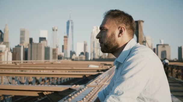 Portrait of happy tourist leaning to Brooklyn Bridge rails, enjoying amazing New York City architecture panorama 4K. — Stock Video