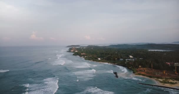 Oiseaux aériens vue aérienne de belles vagues de mer mousseuses se brisant près du rivage tropical avec des arbres verts et un chantier de construction 