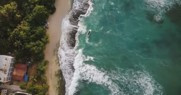 Vôo aéreo drone tiro de costa marinha exótica idílica com pouco barco, espumando ondas brancas colidindo e casas de recurso . — Vídeo de Stock