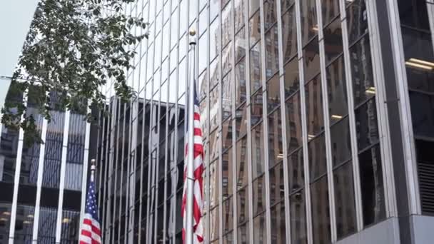 Vista de cerca de edificios de oficinas de rascacielos en Nueva York, Estados Unidos. Bandera nacional americana ondeando en el viento . — Vídeo de stock