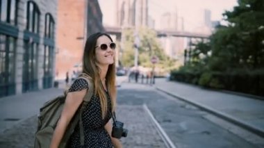Kamera çantada New York şehir sokakları, zevk güneş gözlüğü ile genç heyecanlı kadın turist mutlu 4 k gülümseyen izler