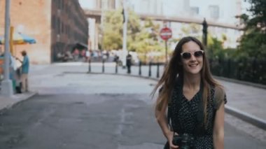 Sırt çantası içinde güneş gözlüğü, eller yükselterek ve mutlu 4 k gülümseyen oynak heyecanlı Avrupa turist kızla kamera izler.