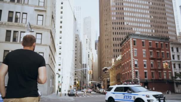 Junger gutaussehender Geschäftsmann mit Dokumenten, der durch das Finanzviertel geht und in New York die Straße überquert. Zeitlupe — Stockvideo