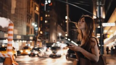 Akşam trafik şehir merkezinde duran ve New York, Amerika smartphone kullanarak genç güzel kadın.