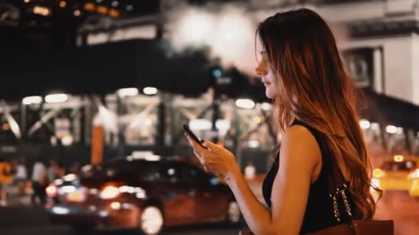 Jeune belle femme debout sur la rue bondée, la circulation à New York, en Amérique le soir et en utilisant un smartphone . — Video