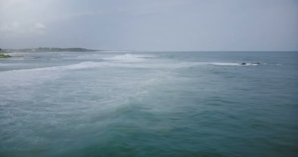 Drone cámara sigue gran ola oceánica alcanzando exótica costa tropical y estrellarse con espuma blanca, dramático cielo junto al mar . — Vídeos de Stock