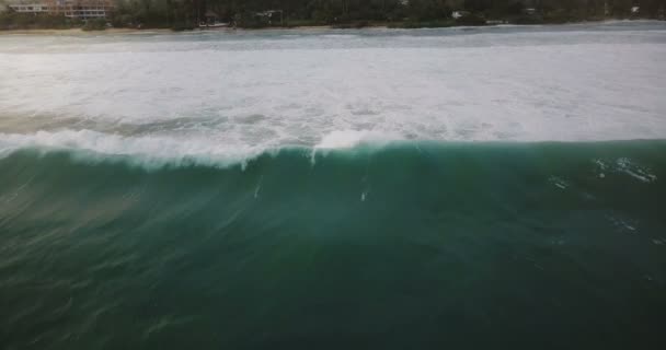 Drone fotocamera segue enorme mare blu onda schiumosa correre verso la bella spiaggia esotica resort con alberi tropicali e case . — Video Stock