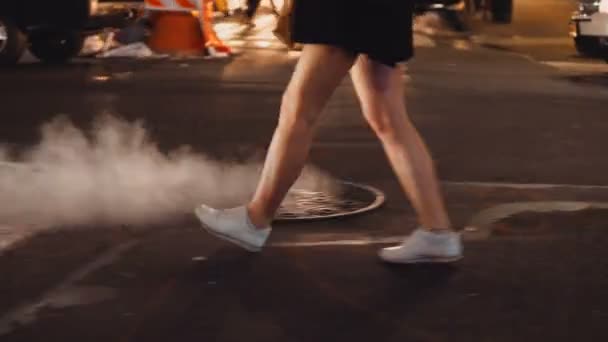 Προβολή με μεγέθυνση νεαρή γυναίκα που διασχίζουν το δρόμο κυκλοφορίας στο κέντρο της πόλης της Νέας Υόρκης το βράδυ και χρησιμοποιώντας το smartphone. — Αρχείο Βίντεο