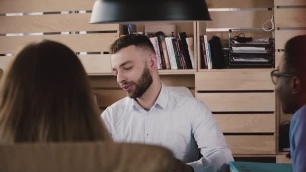 Handsome young Caucasian businessman speaking at multiethnic office meeting in loft trendy coworking slow motion. — Stock Video