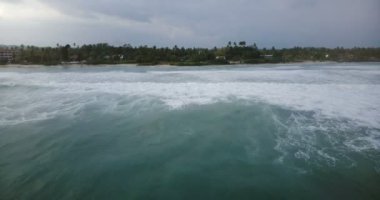 Geriye doğru nefes kesici deniz dalgaları güzel egzotik sahil şeridine tropikal ağaçlar yakınındaki beyaz köpük ile yukarıda uçan robot.