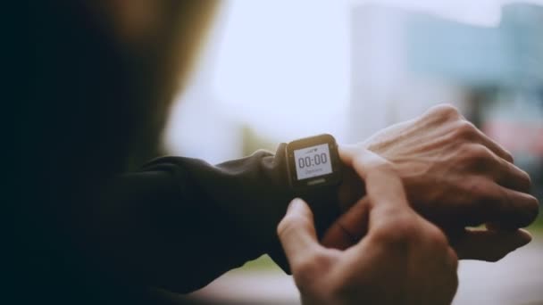 4k Sportsman χρησιμοποιώντας έξυπνο ρολόι χρονόμετρο πριν από την έναρξη. Ο άνθρωπος βλέπει ένα smartwatch tracker χρονόμετρο για να ορίσετε το χρόνο λειτουργίας. — Αρχείο Βίντεο