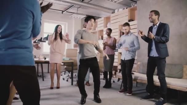 Gelukkig Japanse werknemer doet grappige dans beweegt op toevallige office viering partij. Team viert succes Slowmotion. — Stockvideo