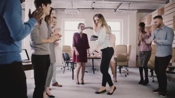 Happy European girl doing moonwalk dance at fun office party. Multiethnic business people celebrate success slow motion. — Stock Video