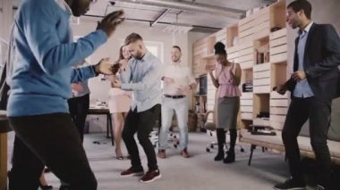 Genç Avrupa işadamı kariyer promosyon ağır çekim kutlama ofis partisinde meslektaşları ile daire içinde dans.