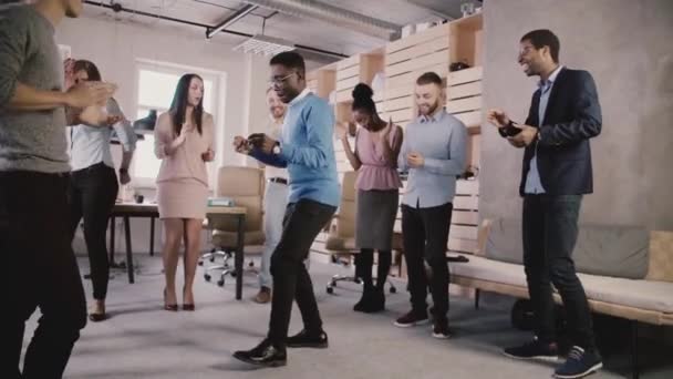 Happy afroamerické šéf tančí se zaměstnanci na teambuilding večírek, oslavu tým úspěch zpomalené.