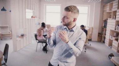 Heyecanlı genç mutlu beyaz işadamı eğlenceli ile başarı kutluyor modern sağlıklı ofis ağır çekimde aptal dans.