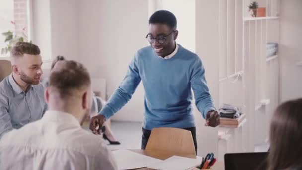 Heureux employé afro-américain faisant danse drôle gagnant dans le bureau moderne, donne haute-cinq à collègue au ralenti . — Video