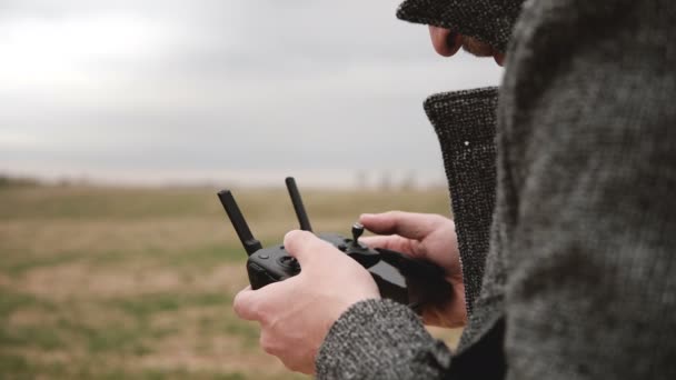 Close-up shot of unrecognizable man looking at black aerial drone remote controller device display on a cloudy day. — Stock Video