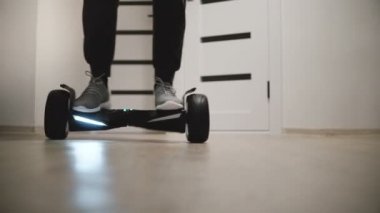 Yakın çekim düşük açılı çekim hareket etme beyaz duvarlar ve kapılar gyro scooter üzerinde spor ayakkabı erkek bacaklar