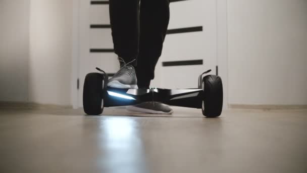 Gros plan angle bas des jambes masculines marchant sur scooter gyroscopique dans l'appartement avec des murs blancs, se déplaçant autour et puis loin — Video