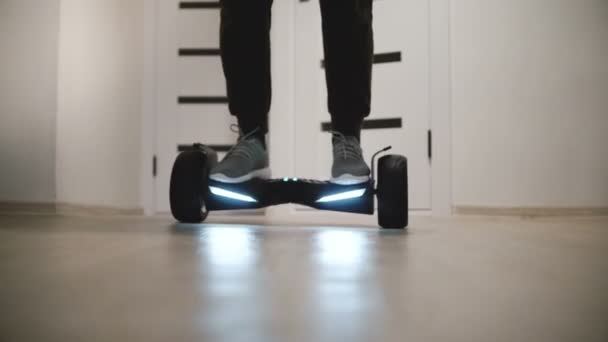 Close-up shot of male legs in sneakers moving around on electric hover board in modern light office with white walls. — Stock Video