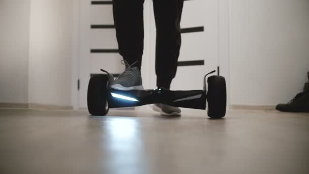 Close-up beeld van mannelijke benen intensivering op elektrische hyroscooter in moderne kantoorruimte met witte muren en bewegen weg. — Stockvideo