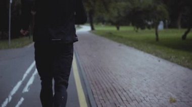 Park yol boyunca koşan adam. Ağır çekim. Arkadan görünüm. Tutma vücut uygun. Güzel bir sessiz parkta koşu sporcu.