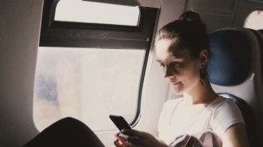 İleti uygulaması üzerinde çalışmak için yol yazarak tren pencere koltukta oturan smartphone kullanarak genç güzel beyaz bir kadın. Çekici emin işkadını Web sitesi Katalog alışveriş üzerinden online satın alma.