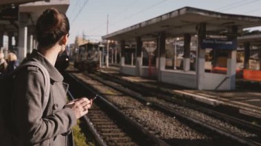 Tren İstasyonu, modern tren platforma geliyor Smartphone sosyal ağ kullanan genç Kafkas banliyö kız