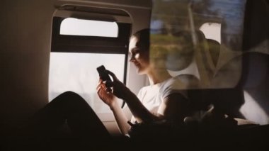 Modern tren pencere kenarı üzerinde seyahat smartphone app üzerinden online satın mutlu güzel beyaz kız inanılmaz çekim.