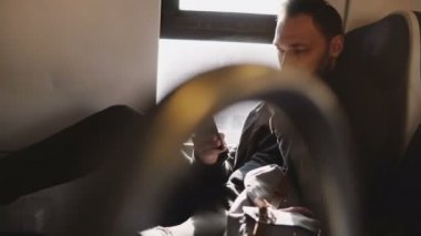 Mutlu rahat gülümseyen Avrupa erkek turist manifatura smartphone messenger App tren pencere kenarı üzerinde seyahat.