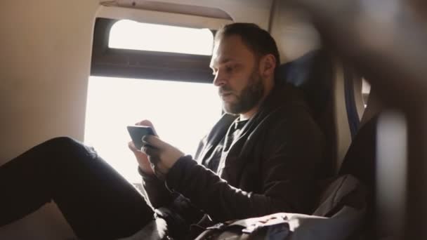 심각한 초점된 유럽 프리랜서 작업자 기차 창이 자리에 여행 하는 스마트폰 메신저 응용 프로그램에 메시지를 입력 — 비디오