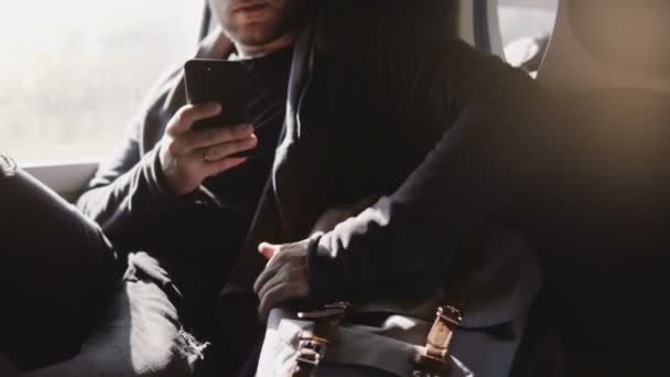 Jistý šťastný úspěšný Evropský nezávislý pomocí smartphone aplikace messenger, kontrola batoh na cestách ve vlaku. — Stock video
