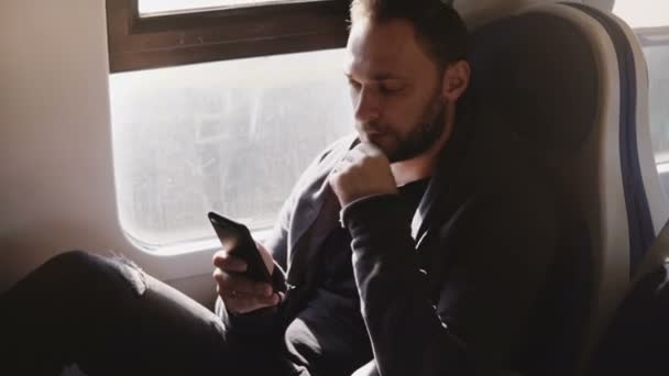 Confiado serio hombre de negocios caucásico mensajes de texto en el teléfono inteligente aplicación de oficina móvil sentado en el asiento de la ventana del tren moderno . — Vídeo de stock