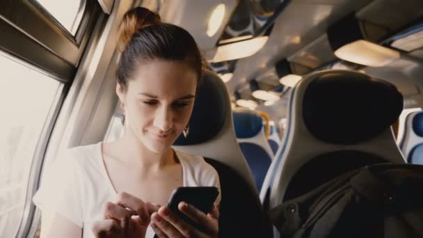 Foto da vicino di una bella ragazza europea felice che utilizza l'app per social network per smartphone che viaggia sul sedile del finestrino del treno . — Video Stock