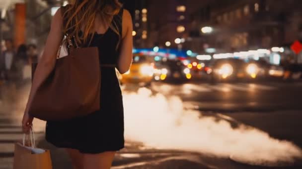 Ung vacker kvinna med shoppingkassar korsande trafik väg med brunnslock, rök i New York, Amerika. — Stockvideo