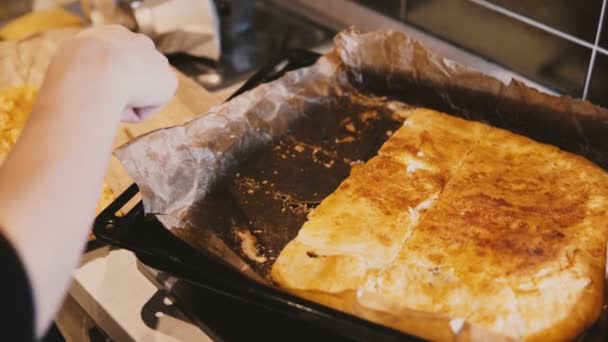 Szczegół widok kobiecych rąk cięcia piękne domowej roboty ciasto złotych na tacy kuchnia i serwowania na stole. — Wideo stockowe