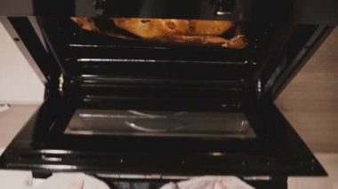 Üstten görünüm eller pot sahipleri ile mutfak fırın açmak, pişirme pan üzerine güzel pasta ile çıkar ve kapatın.