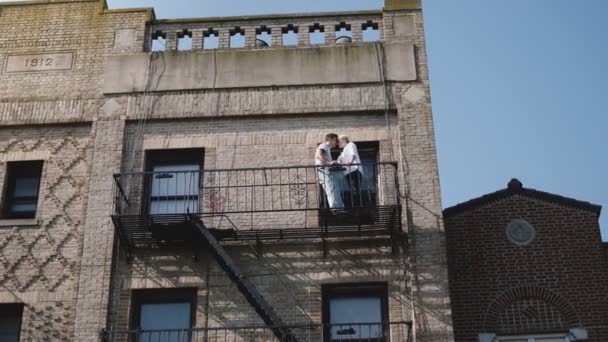 Bela jovem casal romântico de pé juntos em uma pequena varanda do antigo edifício vintage, desfrutando de vista de Nova York . — Vídeo de Stock
