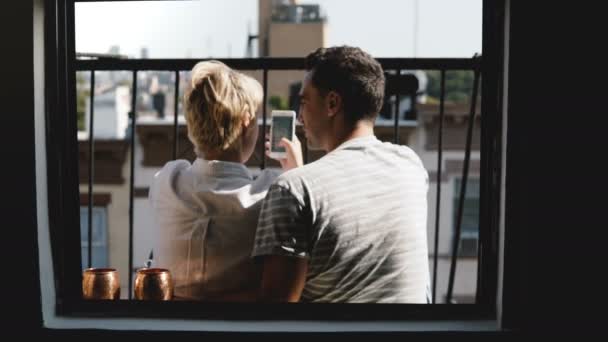 Prieteni tineri fericiți stau împreună la un mic balcon din New York, vedere de la fereastra apartamentului, folosind aplicația de cumpărături smartphone . — Videoclip de stoc