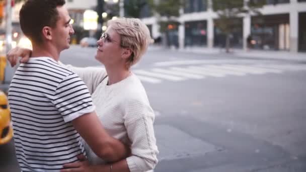 Slow motion jonge man en vrouw samen permanent en knuffelen bij kruising New York street, gele taxi passerende. — Stockvideo